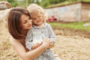 leche natural fresca. la joven madre con su hija está en la granja en verano foto