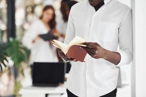 Man with notepad. Group of african american business people working in office together photo