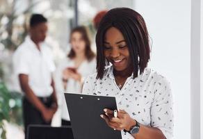 Holding notepad. Group of african american business people working in office together photo