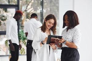 Holding notepad. Group of african american business people working in office together photo