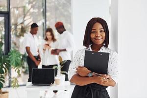 mujer sosteniendo el bloc de notas. grupo de empresarios afroamericanos que trabajan juntos en el cargo foto
