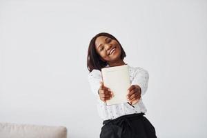 Young african american woman in formal clothes standing with notepad and empty paper in hands indoors photo