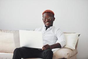 joven afroamericano vestido con ropa formal en el interior con una laptop en las manos foto