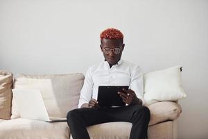 Young african american man in formal clothes indoors with laptop in hands photo