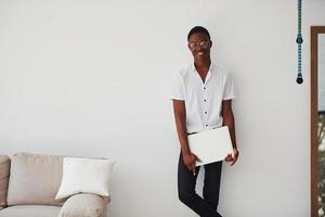 Young african american man in formal clothes indoors with laptop in hands photo