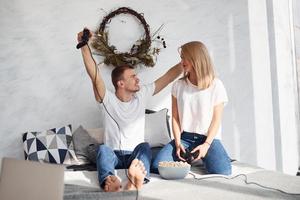 Young lovely couple together at home playing video games on bed with popcorn at weekend time photo