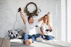 Young lovely couple together at home playing video games on bed with popcorn at weekend time photo