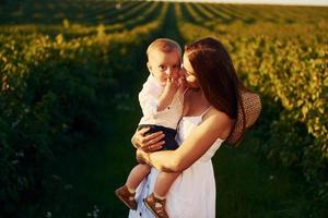 Positive mother with her son spending free time on the field at sunny day time of summer photo