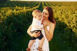 madre positiva con su hijo pasando tiempo libre en el campo en el día soleado del verano foto