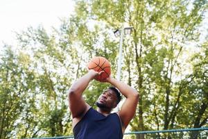 clima nublado. hombre afroamericano juega baloncesto en la cancha al aire libre foto