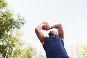 clima nublado. hombre afroamericano juega baloncesto en la cancha al aire libre foto