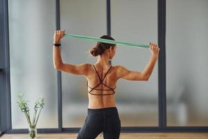 vista trasera. mujer joven en ropa deportiva y con cuerpo delgado tiene un día de yoga fitness en el interior foto