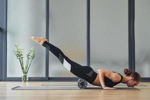 vista desde el lado. mujer joven en ropa deportiva y con cuerpo delgado tiene un día de yoga fitness en el interior foto