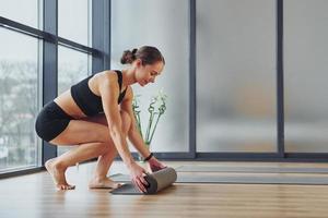 Exercises begins. Young woman in sportive wear and with slim body have fitness yoga day indoors photo