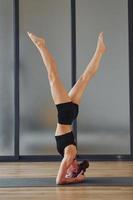 Difficult exercise. Young woman in sportive wear and with slim body have fitness yoga day indoors photo