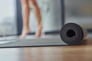 cerrar la vista enfocada en el tapete. mujer joven en ropa deportiva y con cuerpo delgado tiene un día de yoga fitness en el interior foto