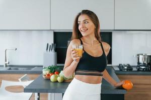 con jugo de naranja fresco. joven europea está en el interior de la cocina con comida saludable foto