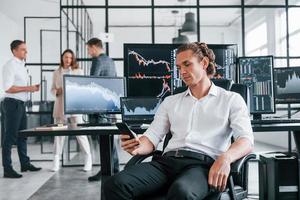 Ordinary office day. Team of stockbrokers works in indoors with many display screens photo