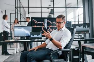 Ordinary office day. Team of stockbrokers works in indoors with many display screens photo