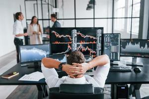 Ordinary office day. Team of stockbrokers works in indoors with many display screens photo