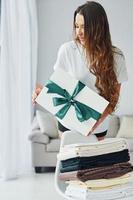 Young woman with white gift box. Interior and design of beautiful modern bedroom at daytime photo