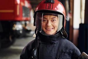 Close up view. Female firefighter in protective uniform standing near truck photo