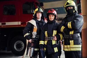 posando para una cámara. grupo de bomberos con uniforme protector que está en la estación foto