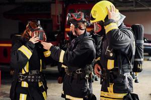 vistiendo uniforme de protección. grupo de bomberos que está en la estación foto