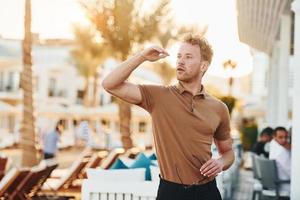 Bright sunshine. Young man is outdoors at sunny daytime. Concept of vacation photo