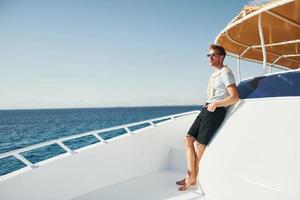 Young male tourist is on the yacht on the sea. Conception of vacation photo