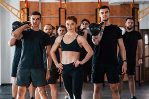 posando para una cámara. grupo de jóvenes deportistas tienen un día de crossfit en el interior del gimnasio foto