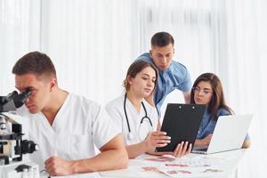 Man with microscope. Group of young doctors is working together in the modern office photo
