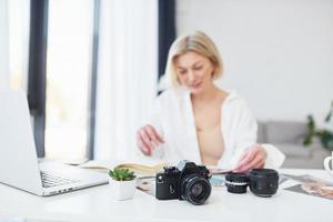 Middle-aged woman in elegant clothes is at home. Photographer with camera photo