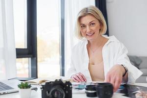 Middle-aged woman in elegant clothes is at home. Photographer with camera photo