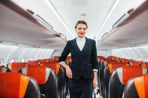 Asientos vacíos. joven azafata en el trabajo en el avión de pasajeros foto