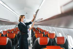 en máscara joven azafata en el trabajo en el avión de pasajeros foto