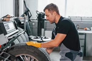 Taking the wheel. Man in uniform is working in the auto service photo