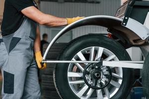 Fixing the tire. Man in uniform is working in the auto service photo