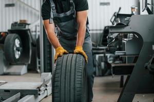 vista de cerca de la rueda. el hombre de uniforme está trabajando en el servicio de automóviles foto