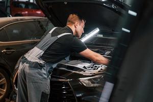 With lighting equipment. Man in uniform is working in the auto service photo