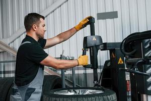 Fixing the tire. Man in uniform is working in the auto service photo