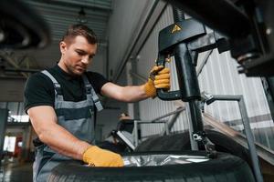 manos fuertes. el hombre de uniforme está trabajando en el servicio de automóviles foto