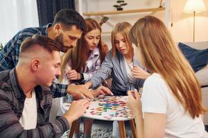 jugando un juego inteligente. grupo de amigos tienen una fiesta en el interior juntos foto