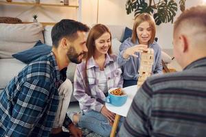 centrado en el juego de construcción de torres. grupo de amigos tienen una fiesta en el interior juntos foto