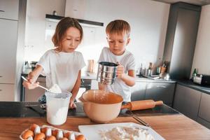 New year anticipation. Little boy and girl preparing Christmas cookies on the kitchen photo