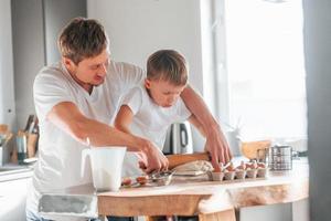 padre enseñando a su pequeño hijo a preparar dulces galletas navideñas foto