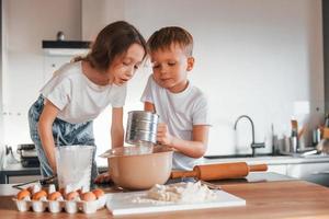 New year anticipation. Little boy and girl preparing Christmas cookies on the kitchen photo