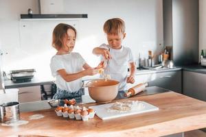 Working with dough. Little boy and girl preparing Christmas cookies on the kitchen photo