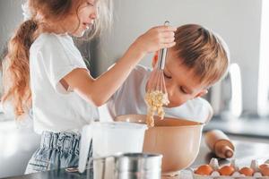 aprendiendo a cocinar. niño y niña preparando galletas navideñas en la cocina foto