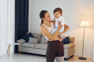 mujer en ropa deportiva con niña. madre con su pequeña hija está en casa juntos foto